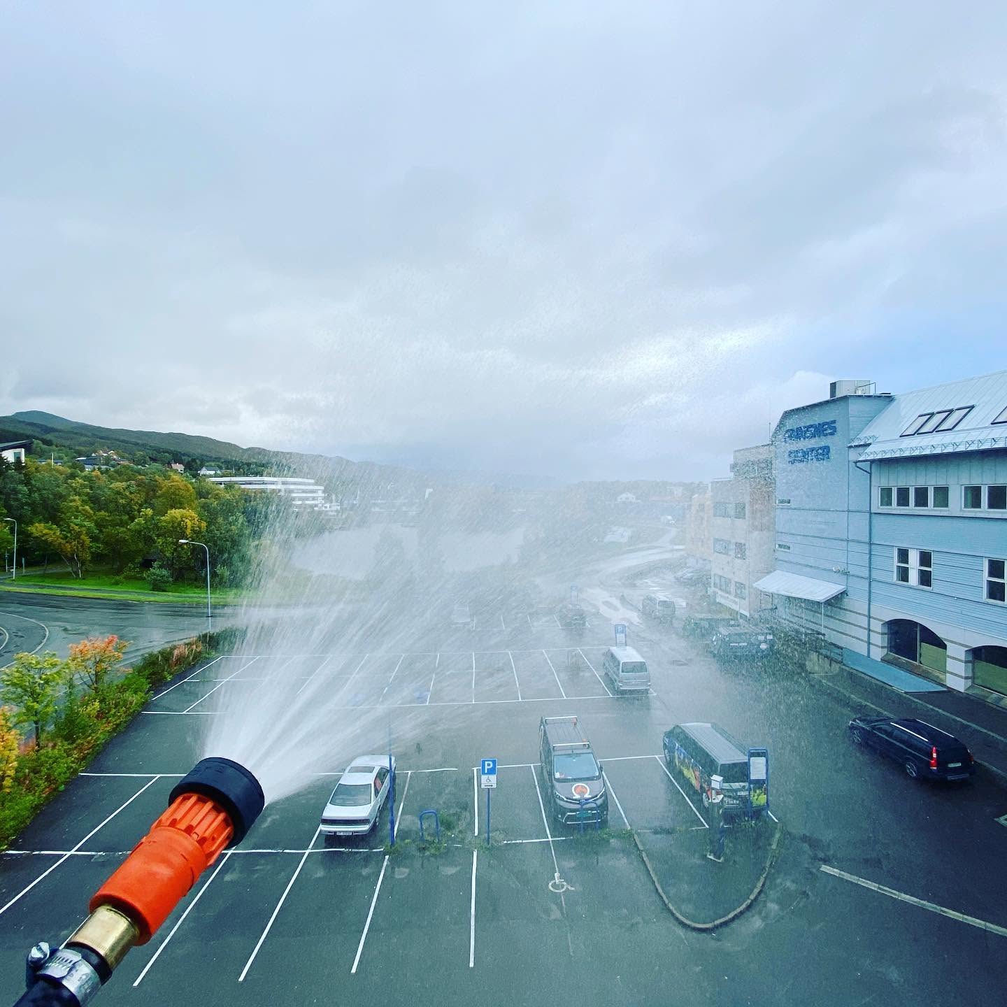 Funksjonstest av brannslange med vannkast over parkeringsplass
